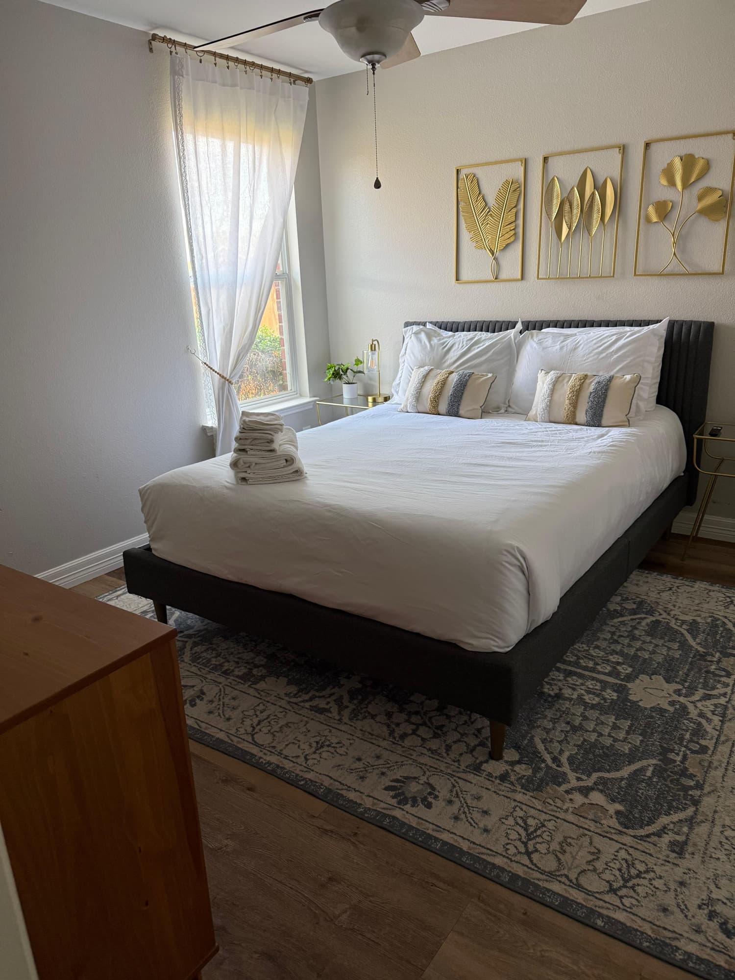 Clean bedroom with white bedding and folded towels on the bed.