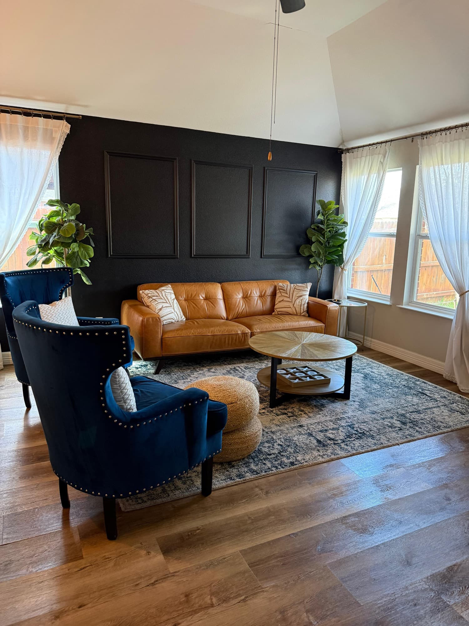Bright living room with clean floors, leather sofa, and arranged pillows.