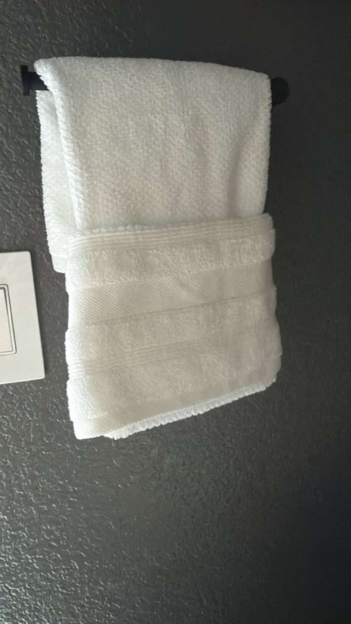 Fresh white towels folded neatly on a bathroom towel bar.
