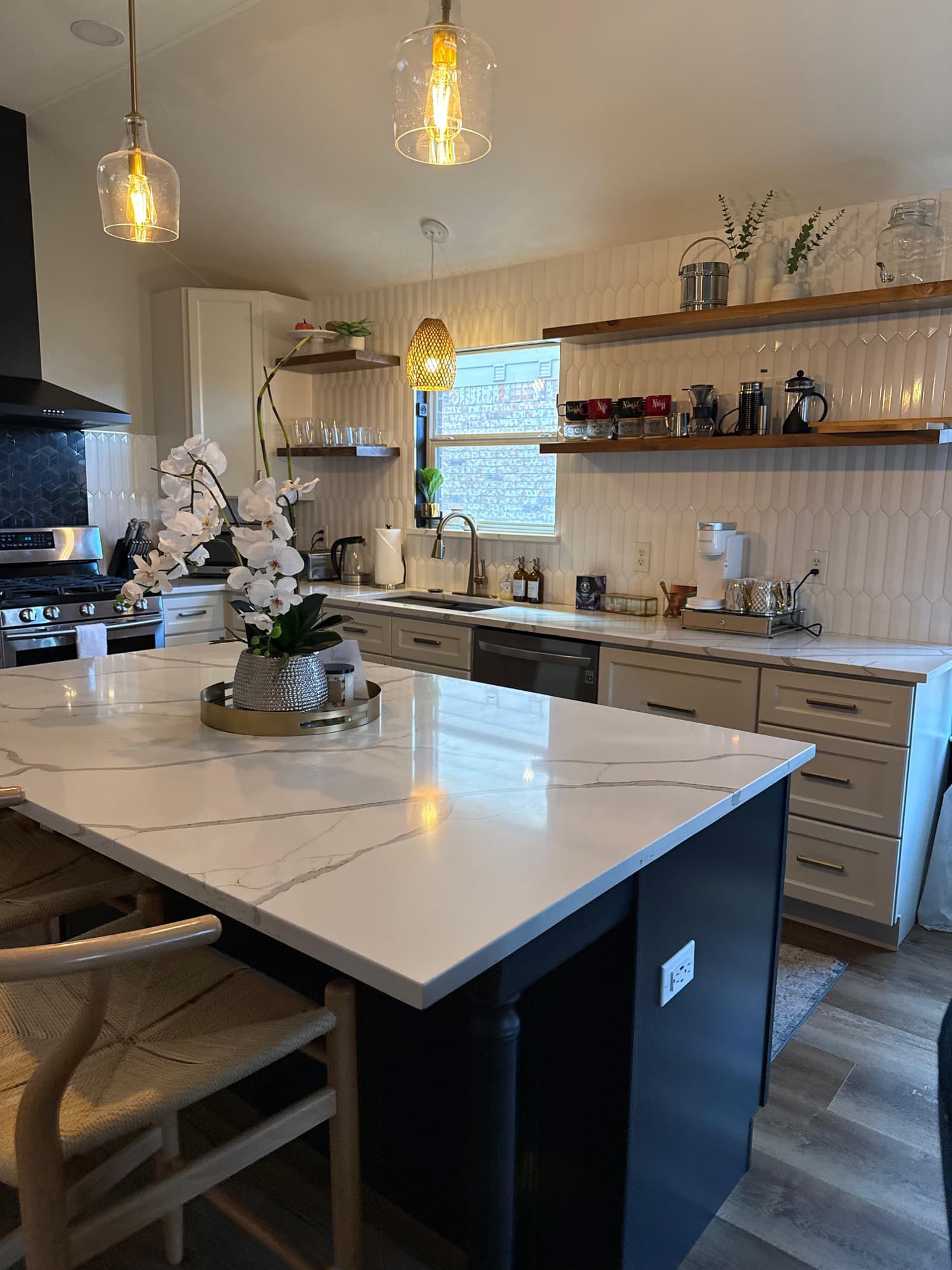 Clean kitchen with polished counters, pendant lights, and styled island.