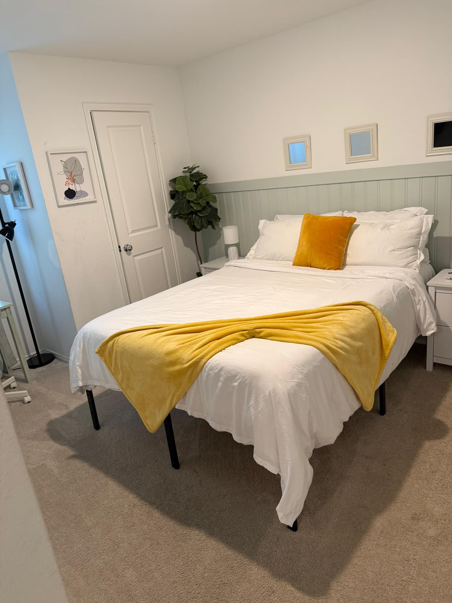 Clean bedroom with white bedding and yellow blanket accent.